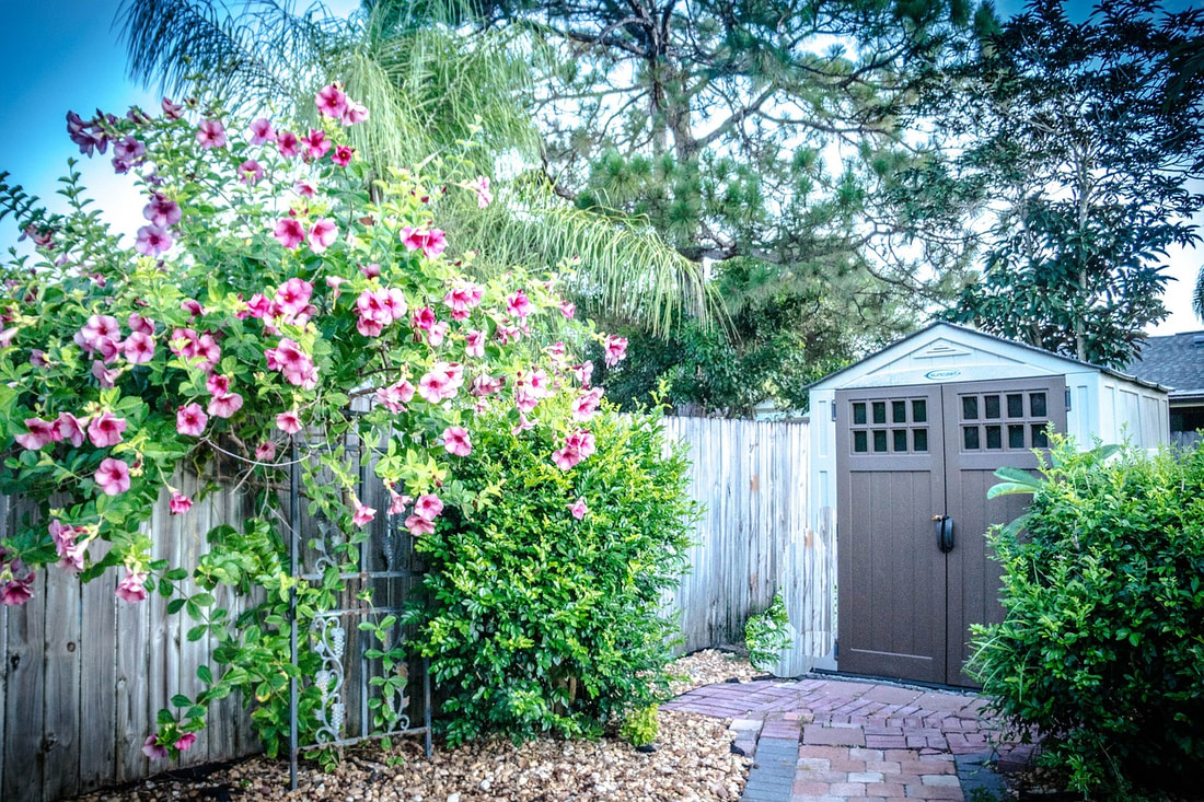 a large shed next to green and pink flowers