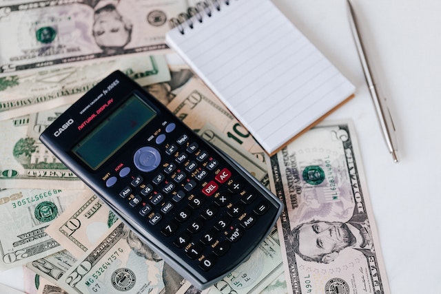 A calculator on top of dollar bills.