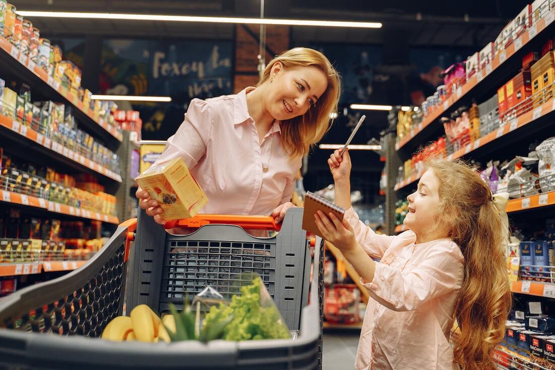 A woman and a child shopping from a list in a store which is one of the tactics that can help you to save money for your first home.Picture