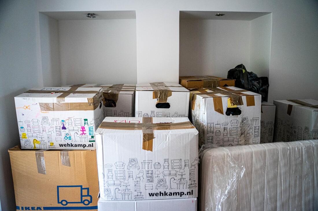A white room filled with numerous different kinds of cardboard boxes filled with items.