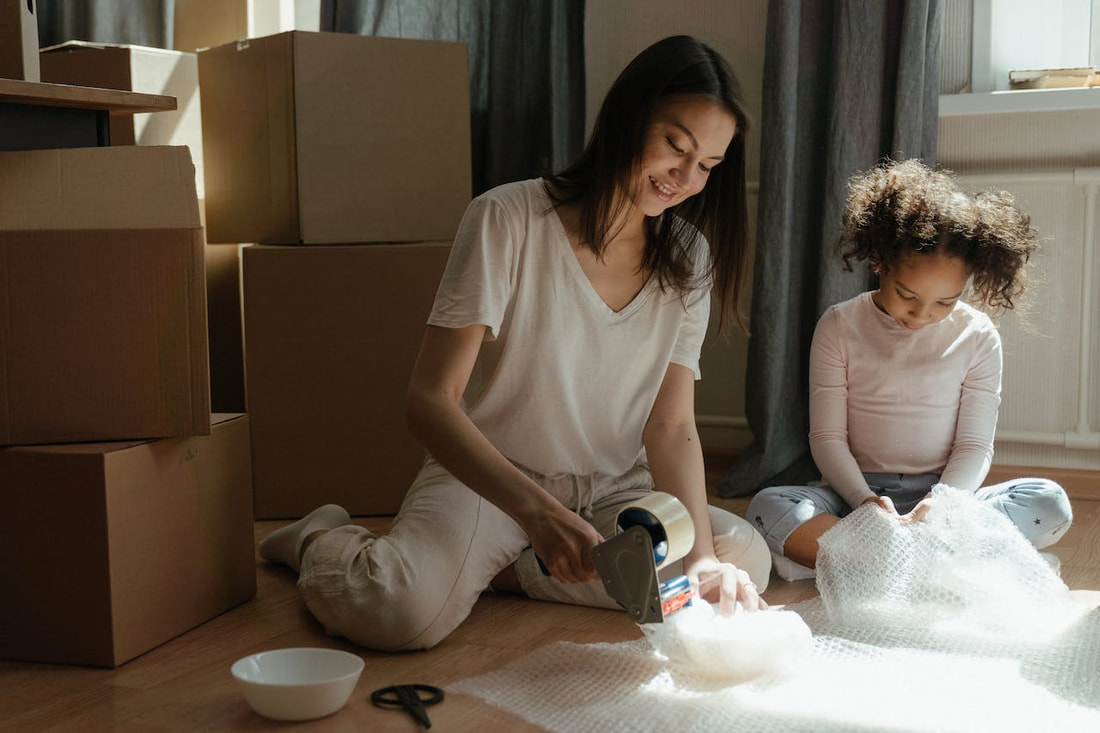 A mother and her daughter wrapping up items while packing for a move.
