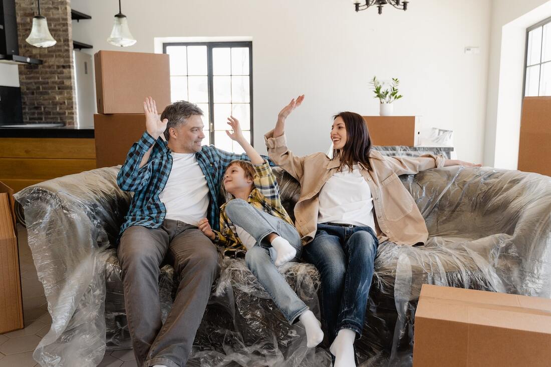 Parents and their son sitting on a couch right after moving in. 
