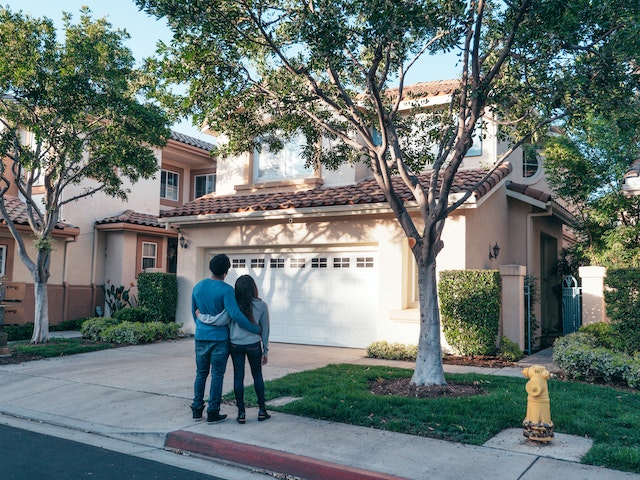 A young couple standing in front of their first house